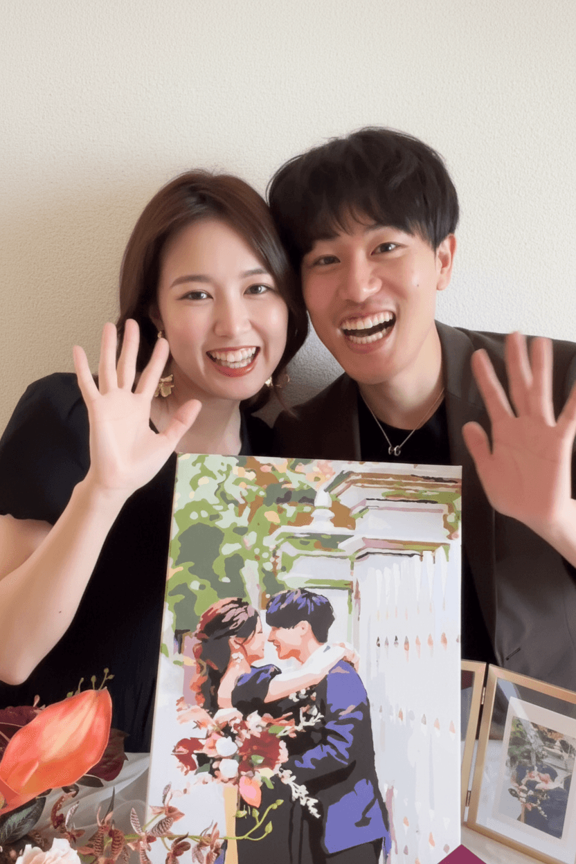 花に囲まれた作品を手に笑顔で手を振るN様ご夫妻